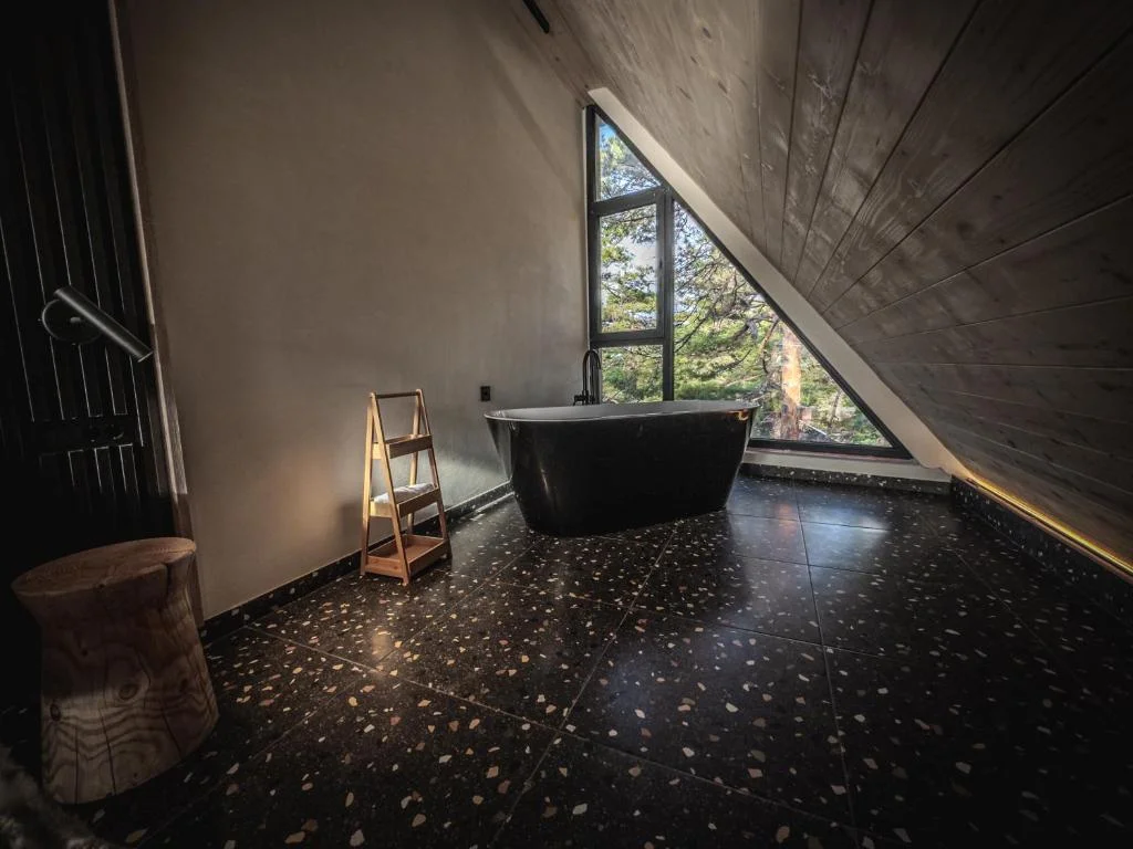 Freestanding black bathtub with triangular forest view window