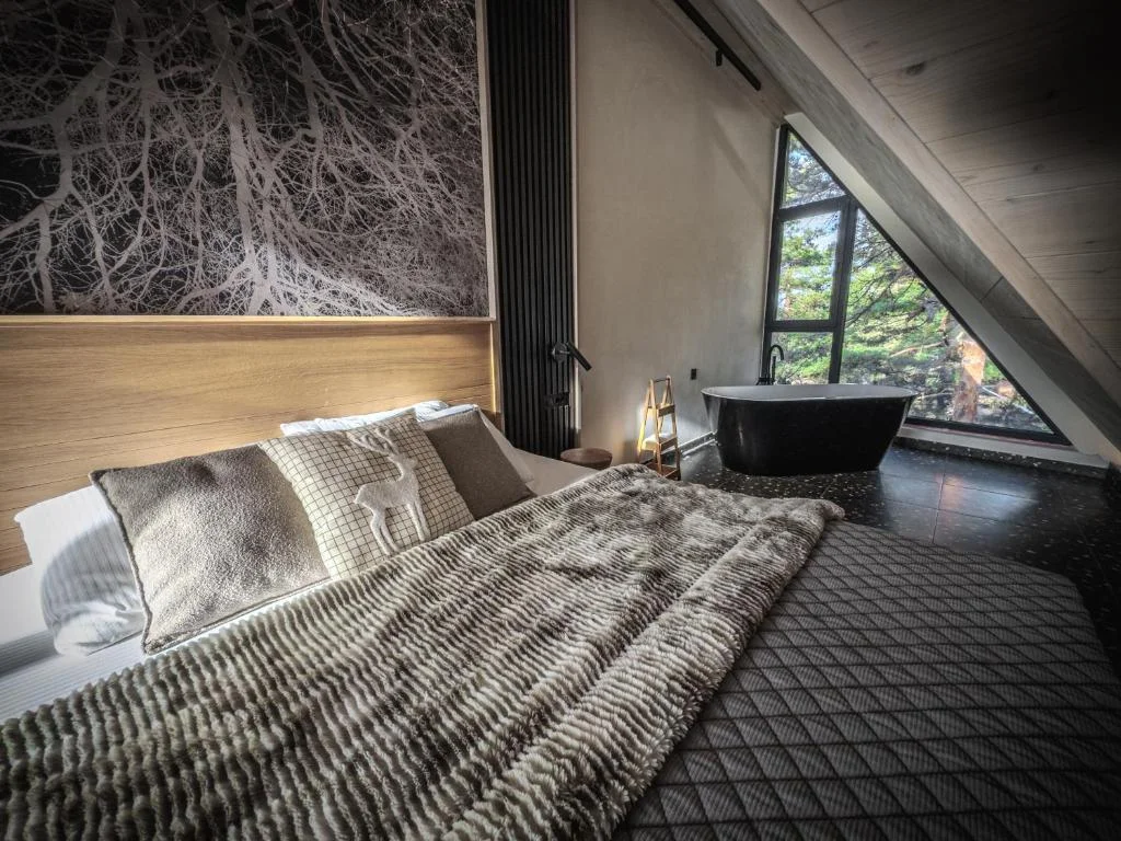 Luxury bedroom with private bathtub and dramatic forest window